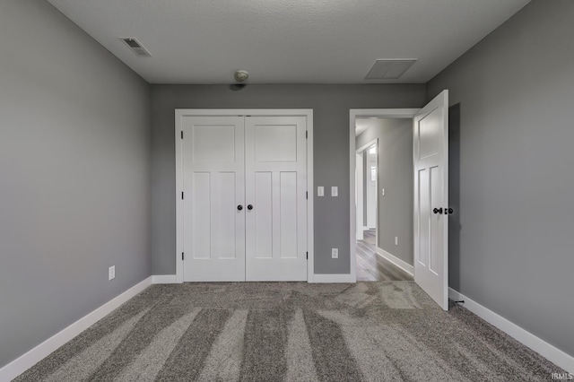 unfurnished bedroom featuring carpet flooring, a closet, and a textured ceiling