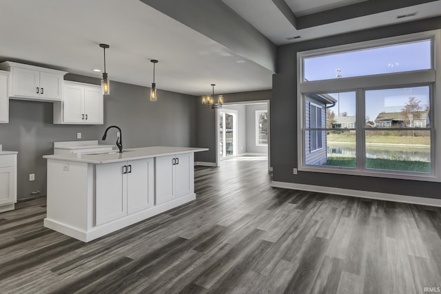 kitchen with sink, dark wood-type flooring, a kitchen island with sink, hanging light fixtures, and white cabinets