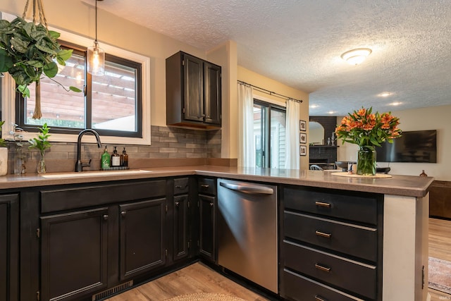 kitchen featuring sink, dishwasher, backsplash, kitchen peninsula, and light wood-type flooring