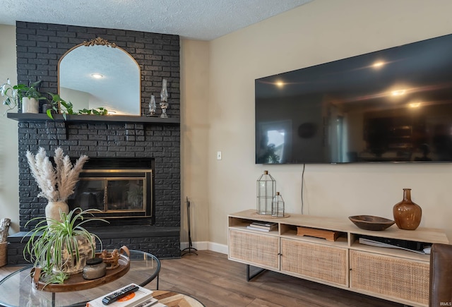 living room with hardwood / wood-style flooring, a textured ceiling, and a fireplace