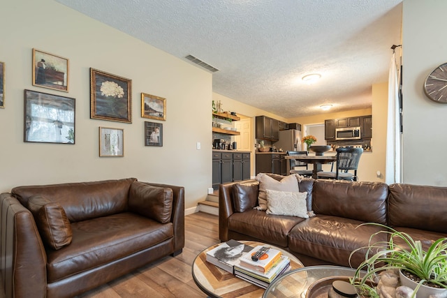 living room with a textured ceiling and light wood-type flooring