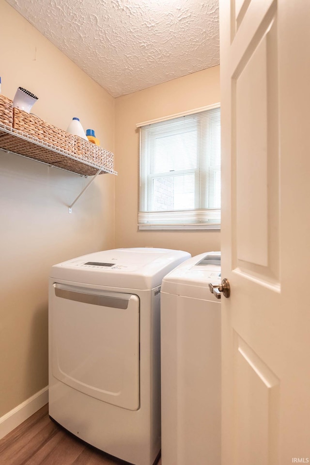 laundry room with hardwood / wood-style floors, washer and dryer, and a textured ceiling