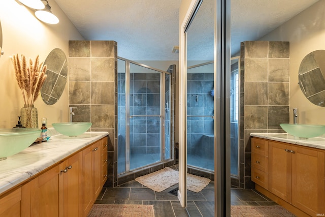 bathroom featuring a shower with door, vanity, and a textured ceiling