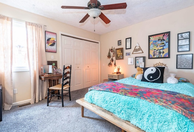 carpeted bedroom with ceiling fan, a textured ceiling, and a closet