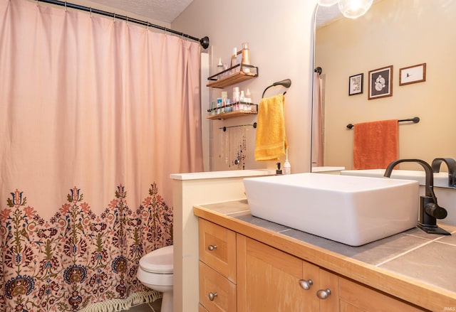 bathroom with vanity, toilet, and a textured ceiling