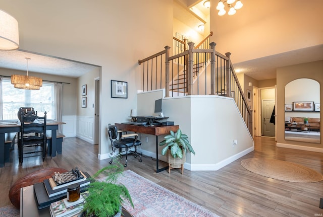 living room featuring a towering ceiling, hardwood / wood-style floors, and a notable chandelier