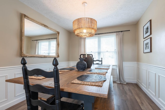 dining space featuring dark wood-type flooring, a chandelier, and a textured ceiling