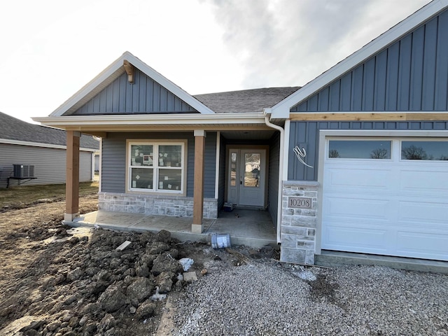 view of front facade with a garage, central air condition unit, and covered porch