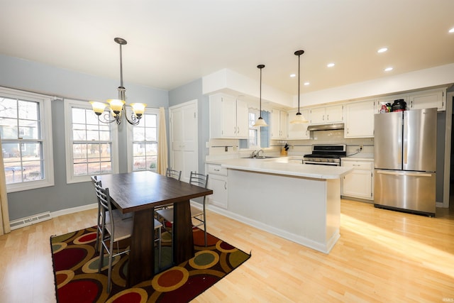 kitchen featuring pendant lighting, stainless steel appliances, light hardwood / wood-style floors, and white cabinets