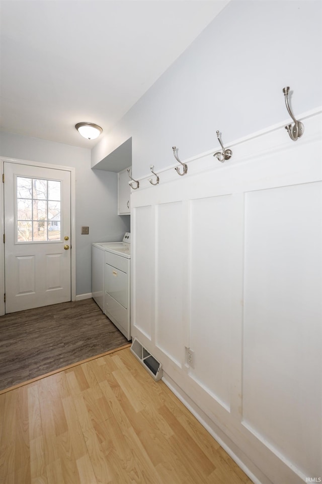 laundry area with washer and clothes dryer, light hardwood / wood-style floors, and cabinets