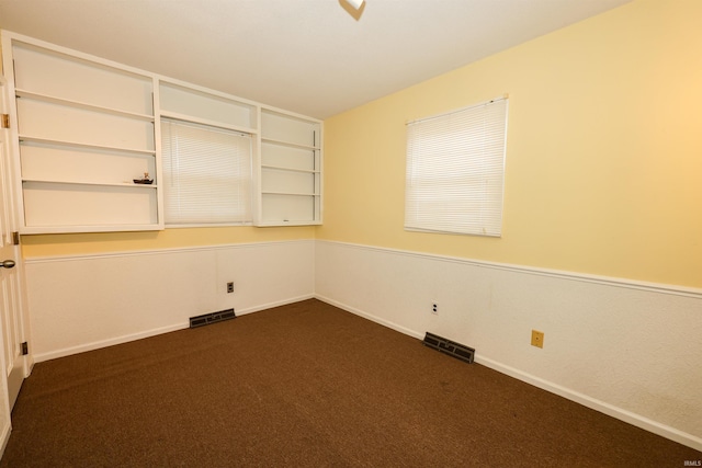 spare room with dark colored carpet