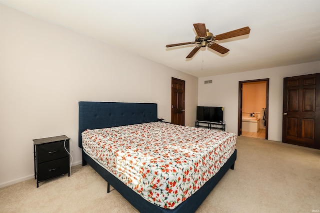 carpeted bedroom with ensuite bath and ceiling fan