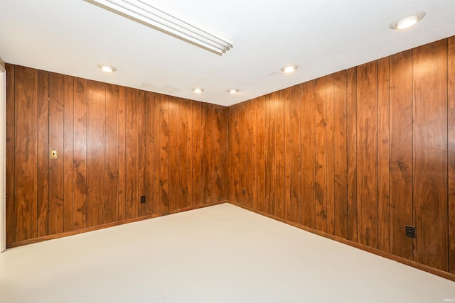 unfurnished room with wooden walls, concrete flooring, and elevator