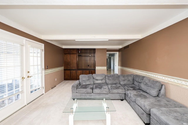 living room featuring beamed ceiling, light colored carpet, and french doors