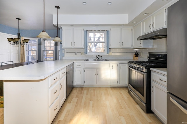 kitchen with decorative light fixtures, white cabinetry, sink, kitchen peninsula, and stainless steel appliances