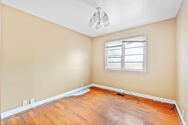 unfurnished room featuring hardwood / wood-style flooring and a chandelier