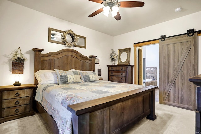 carpeted bedroom featuring a barn door and ceiling fan