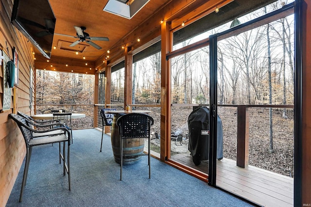 unfurnished sunroom featuring ceiling fan and a skylight