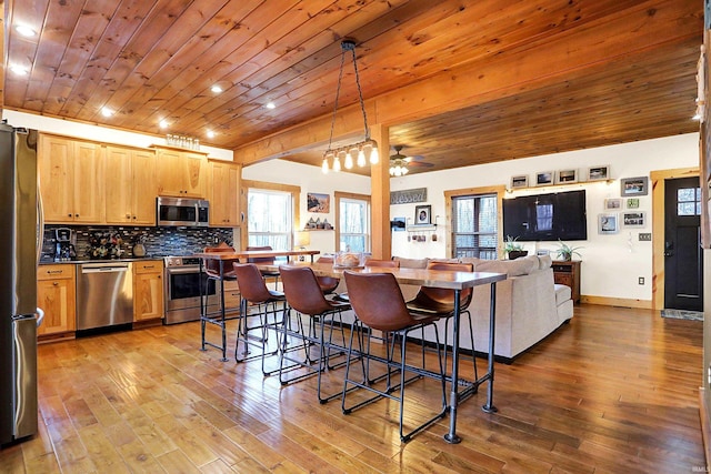 kitchen featuring light wood-type flooring, wooden ceiling, appliances with stainless steel finishes, pendant lighting, and decorative backsplash