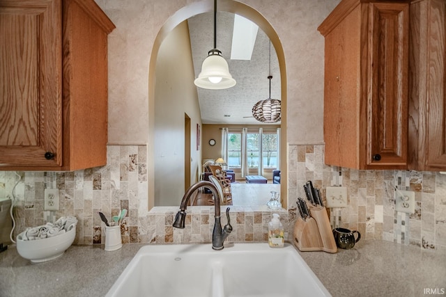 kitchen with pendant lighting, sink, backsplash, and a textured ceiling