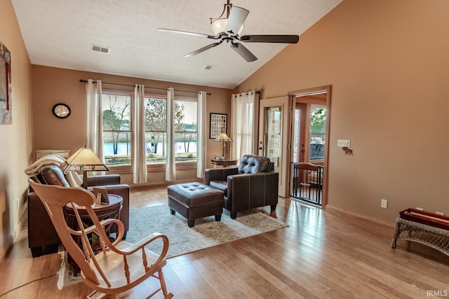 sitting room with lofted ceiling, a textured ceiling, light hardwood / wood-style floors, and ceiling fan