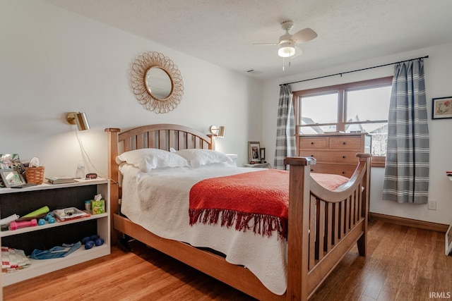 bedroom with ceiling fan, wood-type flooring, and a textured ceiling