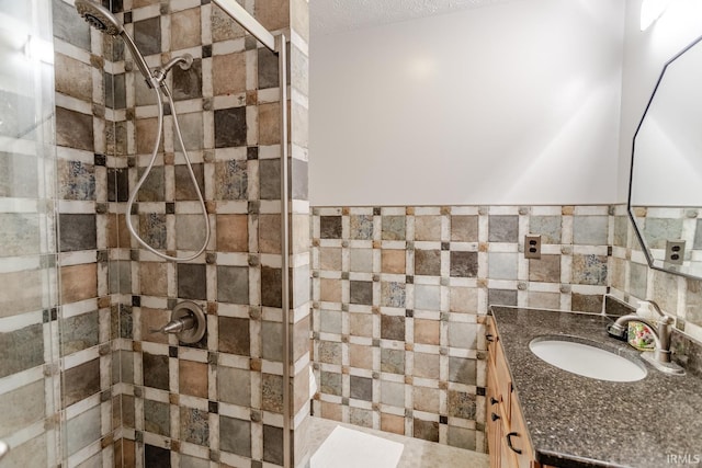 bathroom with vanity, tiled shower, and tile walls