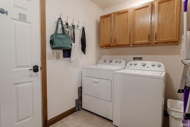 laundry area featuring cabinets, washer and dryer, and light tile patterned floors