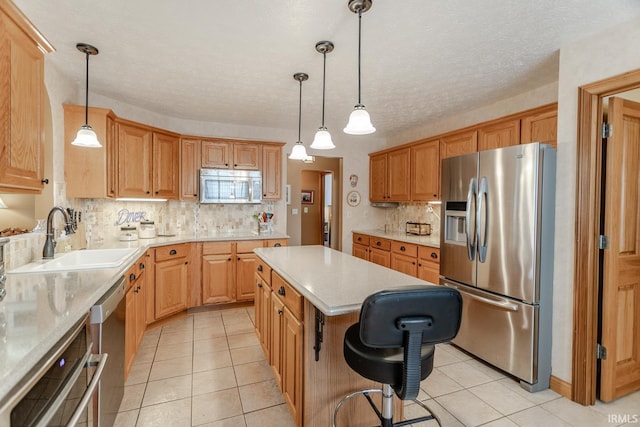 kitchen featuring sink, appliances with stainless steel finishes, a kitchen island, pendant lighting, and decorative backsplash