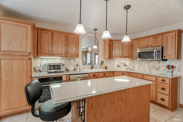 kitchen featuring sink, tasteful backsplash, a center island, hanging light fixtures, and stainless steel appliances