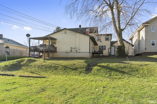 rear view of house featuring a wooden deck and a lawn