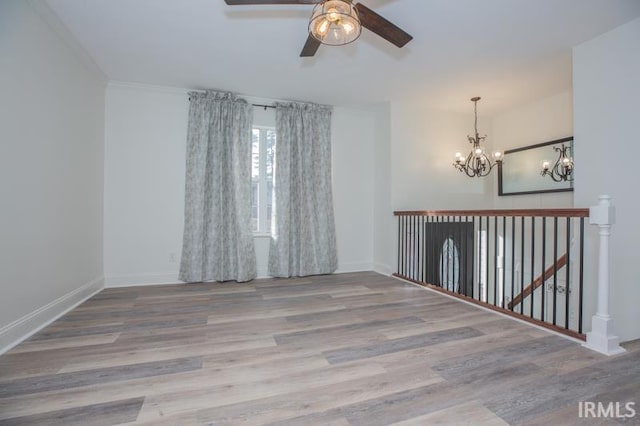 empty room with ceiling fan with notable chandelier and light hardwood / wood-style floors