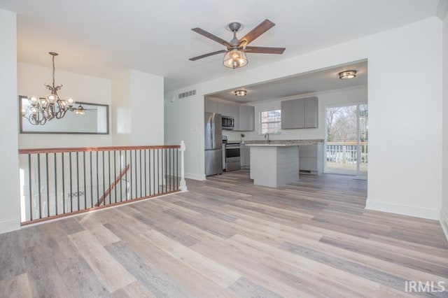 kitchen featuring pendant lighting, light hardwood / wood-style flooring, gray cabinetry, stainless steel appliances, and a center island