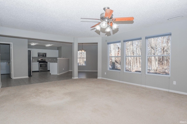 unfurnished living room featuring dark carpet, ceiling fan with notable chandelier, and a textured ceiling