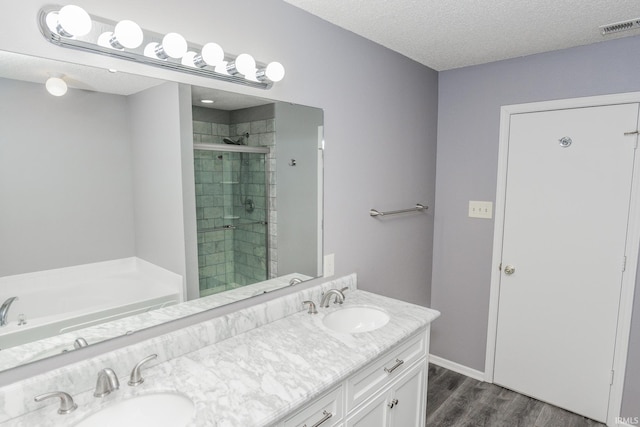 bathroom featuring independent shower and bath, vanity, hardwood / wood-style flooring, and a textured ceiling