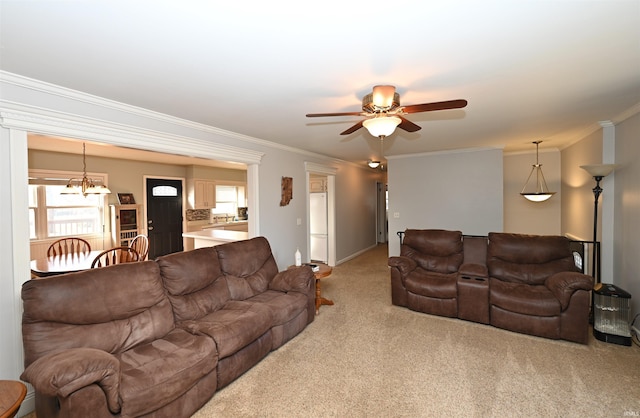 carpeted living room with ornamental molding and ceiling fan with notable chandelier