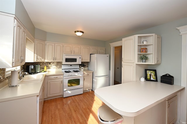 kitchen featuring tasteful backsplash, sink, white appliances, and kitchen peninsula