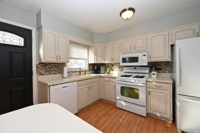 kitchen with backsplash, white appliances, sink, and light wood-type flooring