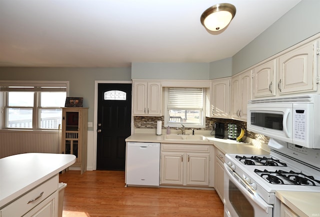 kitchen featuring decorative backsplash, white appliances, sink, and light hardwood / wood-style flooring