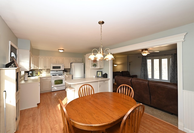 dining space featuring ceiling fan with notable chandelier and light wood-type flooring