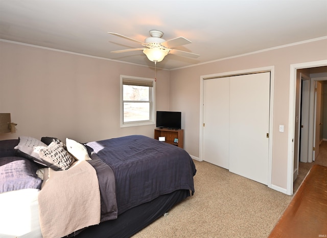 carpeted bedroom with ceiling fan, ornamental molding, and a closet