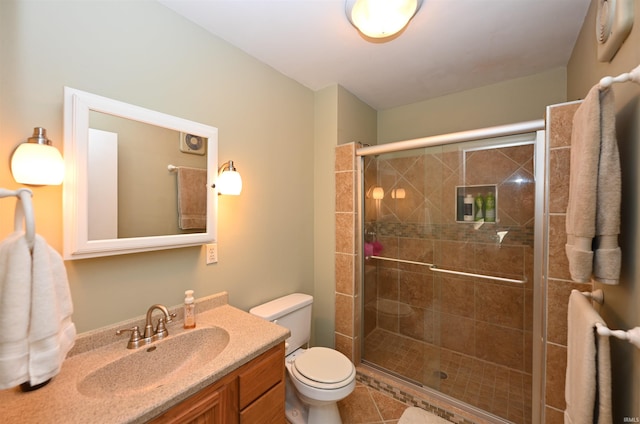 bathroom featuring tile patterned floors, vanity, toilet, and a shower with shower door