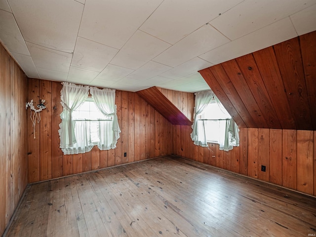 additional living space with a healthy amount of sunlight, wooden walls, and light wood-type flooring