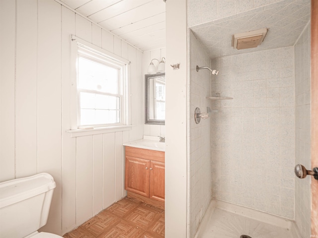 bathroom featuring parquet floors, vanity, toilet, and a tile shower