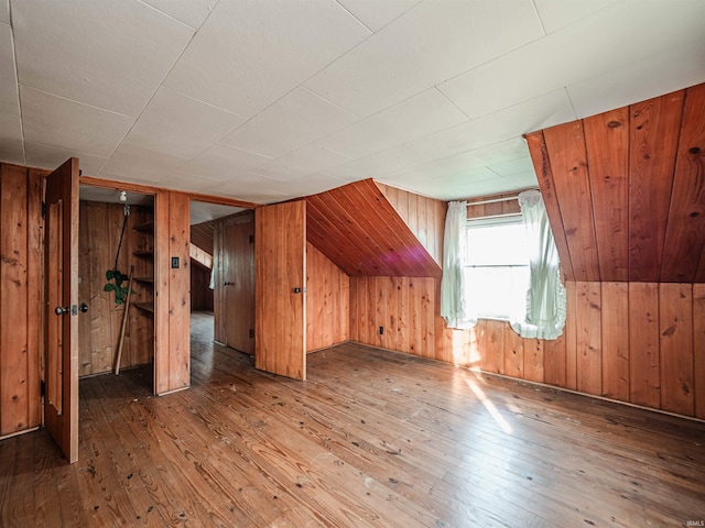 additional living space with wood-type flooring and wood walls