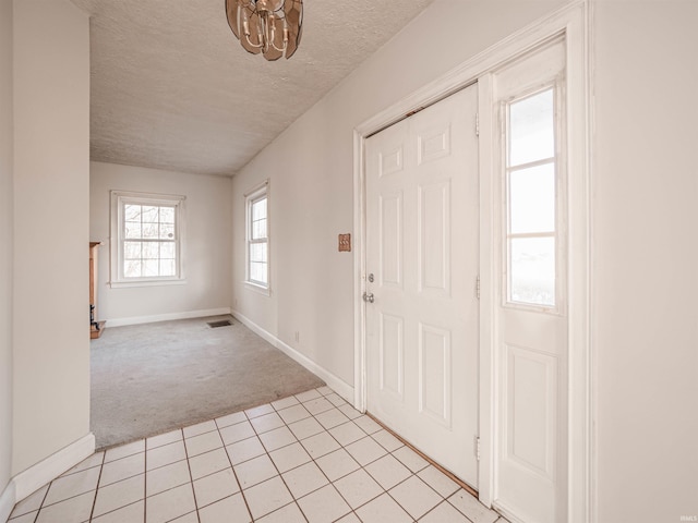 foyer entrance with light colored carpet and a textured ceiling