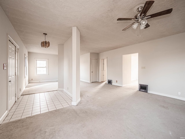 carpeted empty room featuring ceiling fan with notable chandelier and a textured ceiling