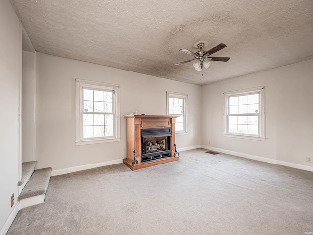 unfurnished living room with a textured ceiling, ceiling fan, and carpet