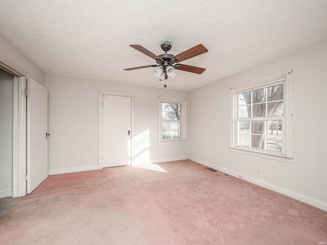 unfurnished bedroom with ceiling fan, light colored carpet, and a textured ceiling