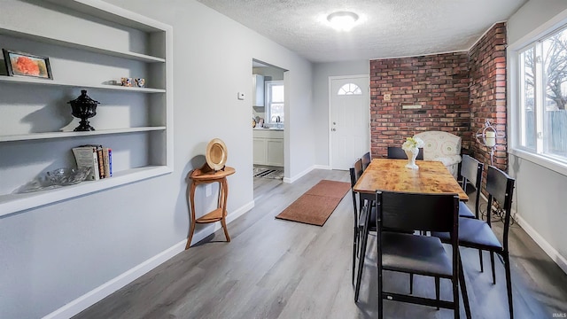 dining space featuring sink, built in features, a textured ceiling, and light wood-type flooring